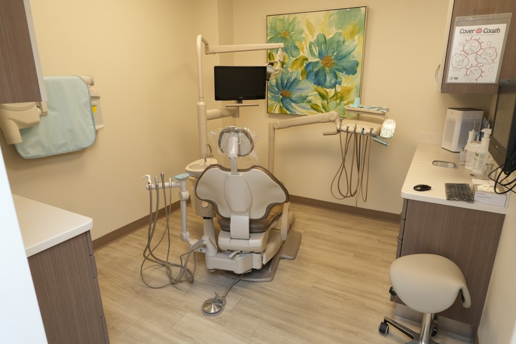 Clean and modern dental exam room with dental chair and instruments.