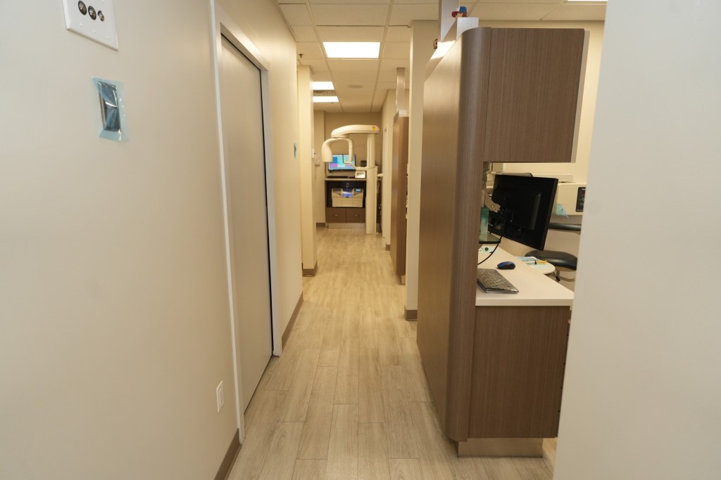 Hallway inside a modern dental clinic with treatment rooms and workstations.